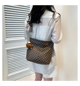 Detail of vintage patterned crossbody bag with striped woven strap and plush charm
