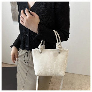Close-up of cream tote bag featuring marble texture and unique knotted handle details