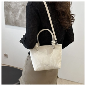 Detail of cream leather bucket bag showing knot handle and marble texture surface
