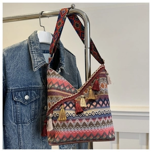 Detailopname van een geweven boho-tas met kleurrijke geometrische patronen en franjes