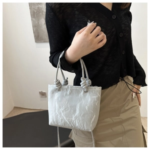 Detailed view of light gray wrinkled texture and knotted handle on the fashion handbag