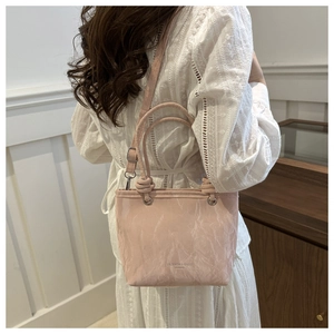 Detail of pink pleated bucket bag showing texture and stylish metal strap attachment