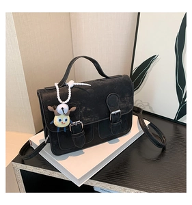 Close-up of vintage black leather bag with double silver buckles and yellow charm