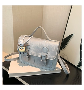 Close-up of silver crossbody bag with dual buckles and cute cartoon charm detail