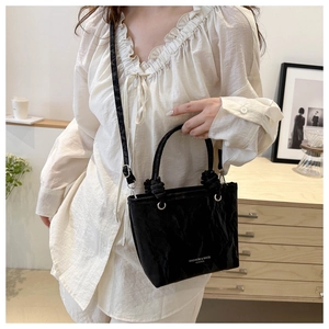 Detail of black textured bucket bag showing wrinkled leather pattern and detachable strap
