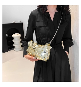 Close-up of sparkling gold sequin chain crossbody bag on a black dress model