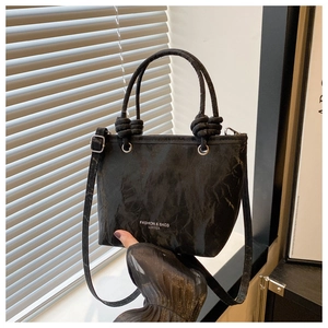 Detail of black wrinkled leather texture on a bucket bag with fashion print and knot detail