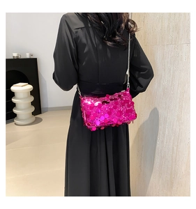 Detail of pink sequin crossbody bag with metallic chain on a black dress backdrop