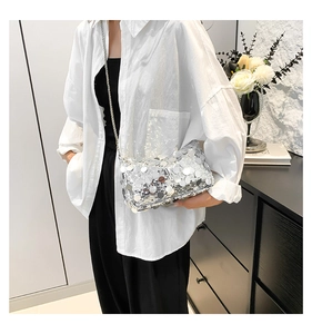 Detail of silver sequin crossbody bag with metallic chain and textured reflective surface