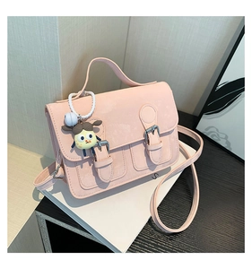 Detail view of pink matte crossbody bag with double buckle straps and cartoon doll charm