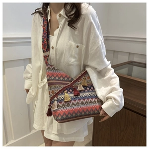Detail van geweven boho crossbodytas met kleurrijke kwastjes en geometrische golfpatronen