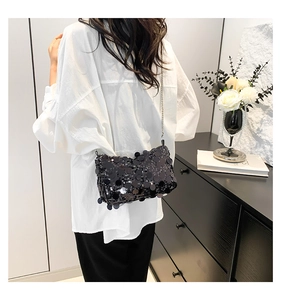 Close-up of black sequin crossbody bag with a delicate silver chain strap on shoulder