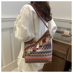 Detail van boheemse crossbodytas met etnische weefpatronen en decoratieve rode kwastjes