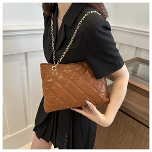 Detail of brown quilted leather tote bag with elegant golden chain shoulder strap