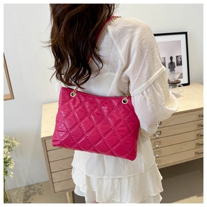 Detail of fuchsia quilted tote bag featuring golden chain strap and soft glossy texture
