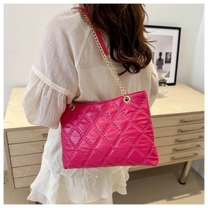 Fashionable pink quilted tote bag with golden chain straps worn by a model in interior