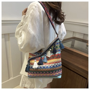 Detail van een geweven bohemian crossbodytas met kleurrijke kwastjes en geometrische patronen