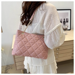 Detailed close-up of pink quilted tote bag with golden chain strap on model shoulder