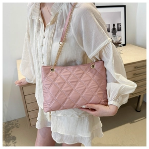 Detail view of pink quilted nylon tote bag with golden chain strap on model