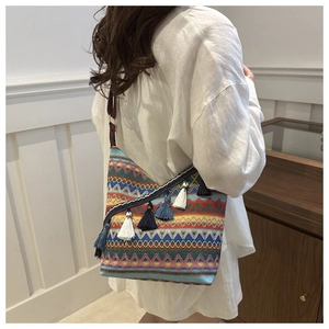 Detail van de boheemse geweven crossbodytas met kleurrijke geometrische patronen en kwastjes