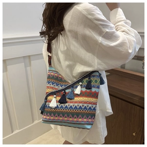 Detail van bohemien geweven crossbodytas met blauwe franjes bij een model