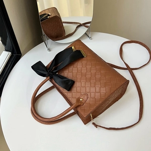 Sac fourre-tout tressé caramel avec nœud en soie noire et boucle dorée, vue de profil