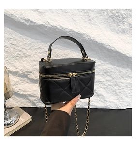 Detail of black quilted leather box bag with gold chain strap and top handle