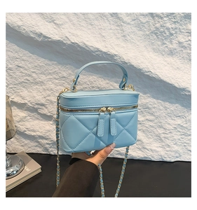Detailed view of light blue quilted mini box bag with gold chain strap and top handle