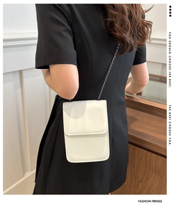 Rear view of a white mini leather phone bag with a slim metal chain on a black dress