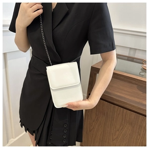 Close-up of white mini crossbody phone bag with metal chain strap on model