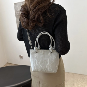 Minimalist grey textured leather bucket bag with top handles and adjustable strap