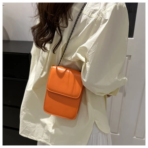 Détail d'un mini sac à rabat orange vif en cuir PU avec une bandoulière en chaîne noire