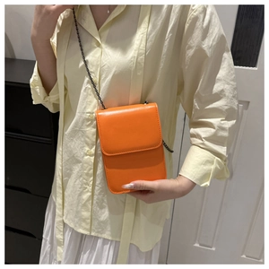 Detailed view of orange PU leather phone bag with black metal chain on female model