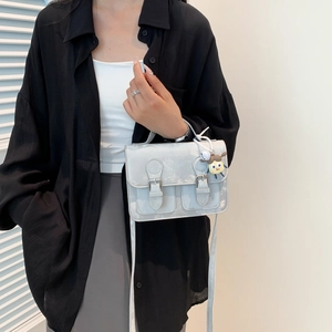 Vintage light gray satchel bag with retro texture and cute doll keychain on black outfit