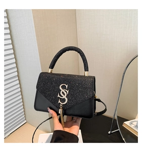 Detail of black crossbody bag featuring sparkly sequins and gold S-logo with tassel