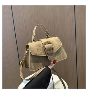 Detail of light brown suede handbag featuring a gold woven texture metal buckle