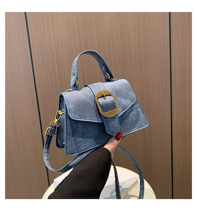 Detail of light blue denim texture crossbody bag with textured gold square buckle