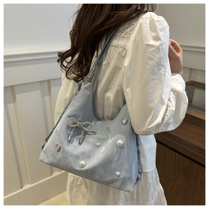 Detail of light blue tote bag with pearl bow and heart rhinestones on metal chain