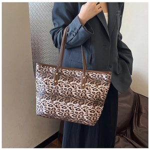 Grand sac cabas à imprimé léopard avec anses en cuir porté par un mannequin en tenue