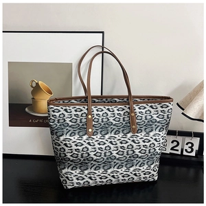 Gros plan d'un sac cabas léopard avec bordure en similicuir marron et détails de rivets dorés