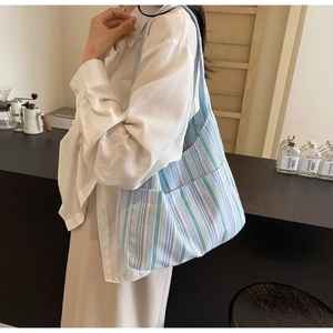 Detail of blue and green striped canvas tote bag showing side pocket in cafe setting