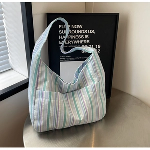 Detail of colorful striped canvas tote bag with front pocket on a metal table