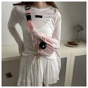 Detail of pink crossbody chest bag with wavy texture and plush ball charm accessory
