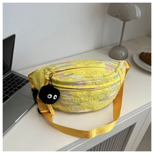 Detail of yellow nylon chest bag with colorful stripes and fuzzy mascot charm