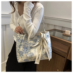 Close-up of floral tote bag with silver chain handle and decorative ribbon on side