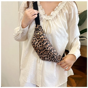 Detail of leopard print waist bag with gold zipper worn over white pleated shirt