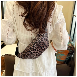 Close-up of leopard print crossbody bag with crescent shape and adjustable black strap