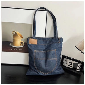 Λεπτομερής προβολή της τσάντας denim με πορτοκαλί ραφές και δερμάτινο vintage σήμα