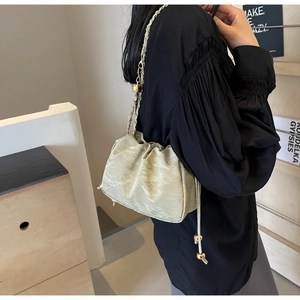 Detail of pleated leather cloud bag featuring a drawstring closure and gold ball chain
