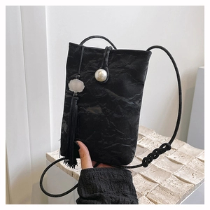 Detail of black pleated phone bag featuring a large pearl button and long silk tassel